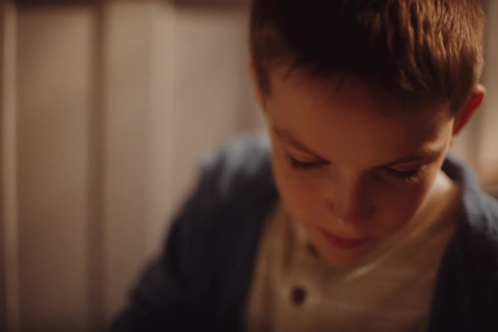 The face of a little boy who is looking at some objects intently