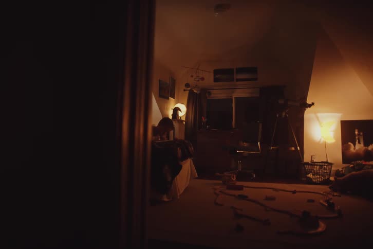 A person lying in bed moving their feet up and the room is dark with yellow lights on