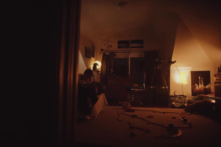 Boy lies on his bed writing during the evening