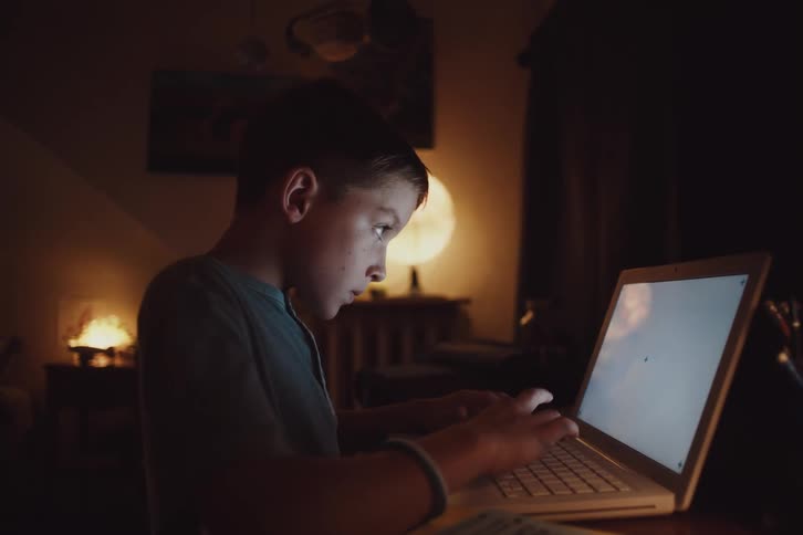 Boy in a room typing on a laptop