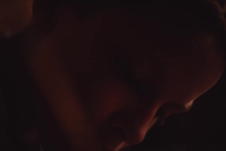A boy is writing in a dark room