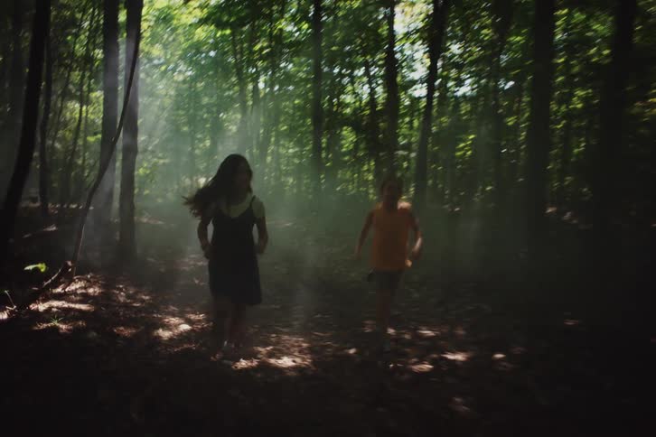 Two children a girl and a boy are joyfully running through a sunlit forest with beams of light filtering through the trees creating a dreamy and lively atmosphere