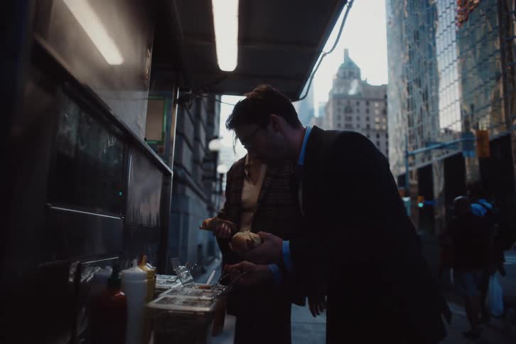 A man is putting toppings on his hot dog at the food truck