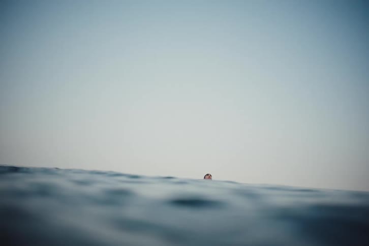 A mans head emerges from the choppy waters of the ocean