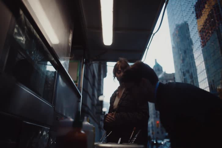 Man and a woman talk as they stand outside a food truck