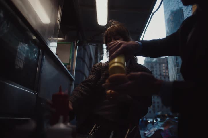 Woman and a man in a food truck putting ketchup on a hot dog