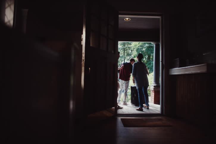 Parents standing on the porch watch their son leave with his girlfriend