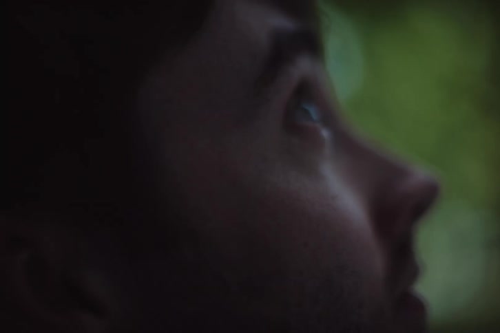 A closeup side profile of a persons face looking upward with soft natural light in the background