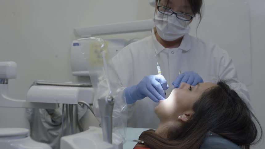 A woman is getting her teeth cleaned by a dentist