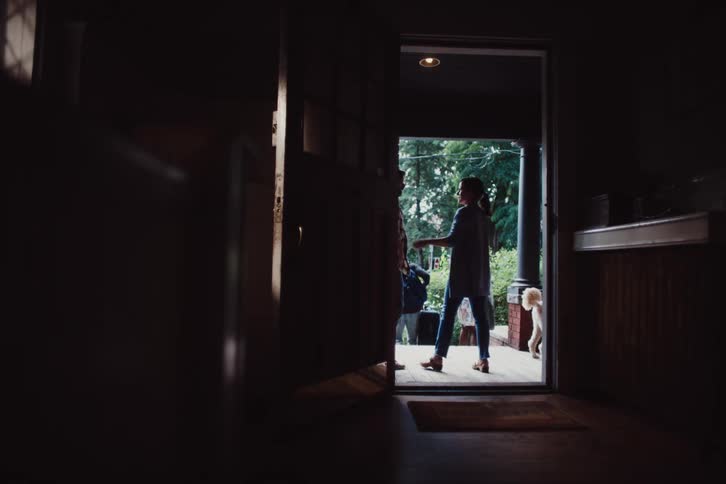 View of a hallway and an open door in the background with people greeting each other and a dog
