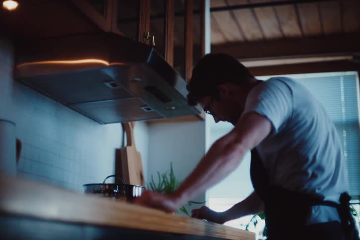 Man in kitchen with apron cooking in front of stove