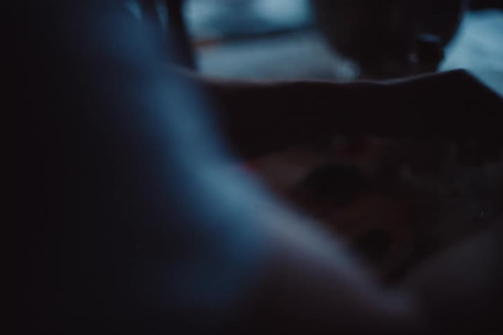 A close up low light view of hands preparing food in a kitchen