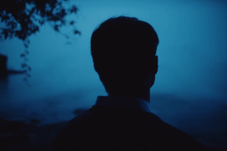 Man stands outdoors staring at fog covered terrain