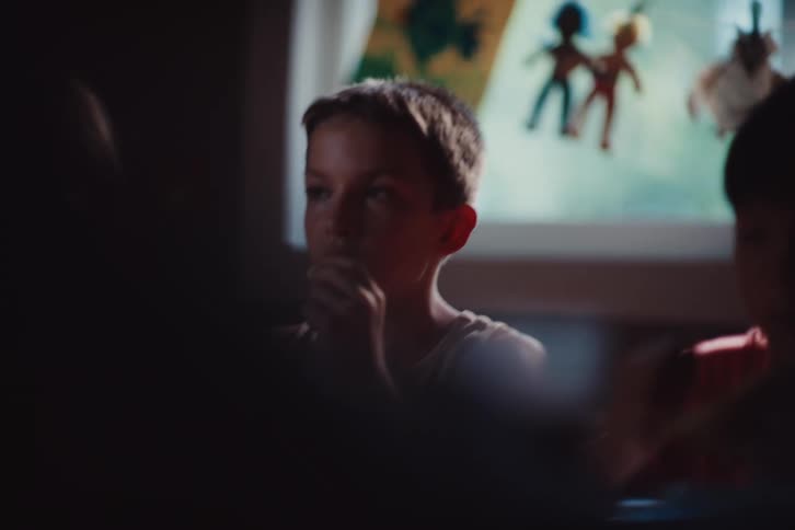 Boy laughs while eating with friends indoors during the day