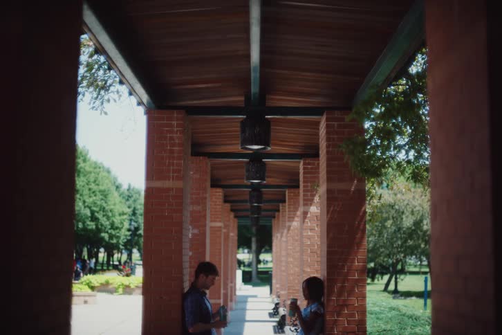 A man and woman talk and drink outside