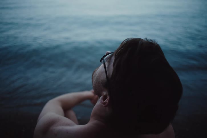 A man is sitting on the shore line