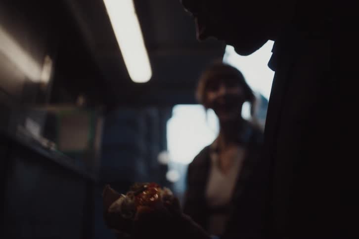 Man and woman holding sandwiches and talking in a diner