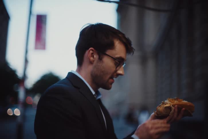Man seasoning a hot dog at a food truck and walks away next to a woman