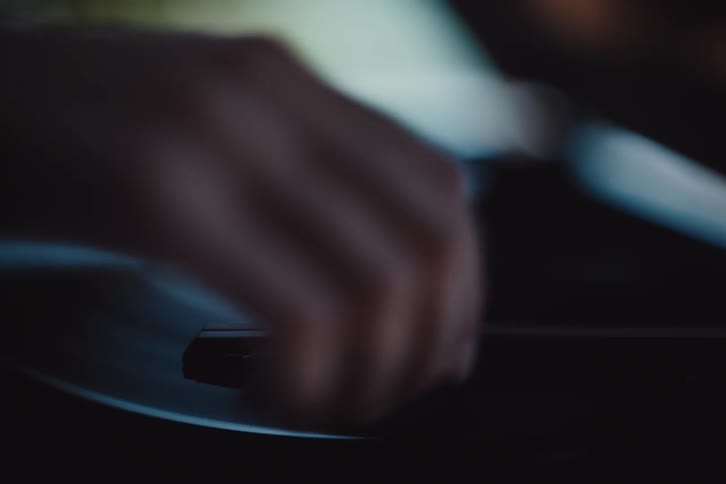 Hand putting a vinyl record player to play