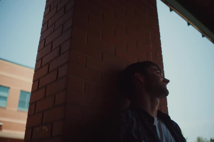 Man leaning against a column in an outdoor area