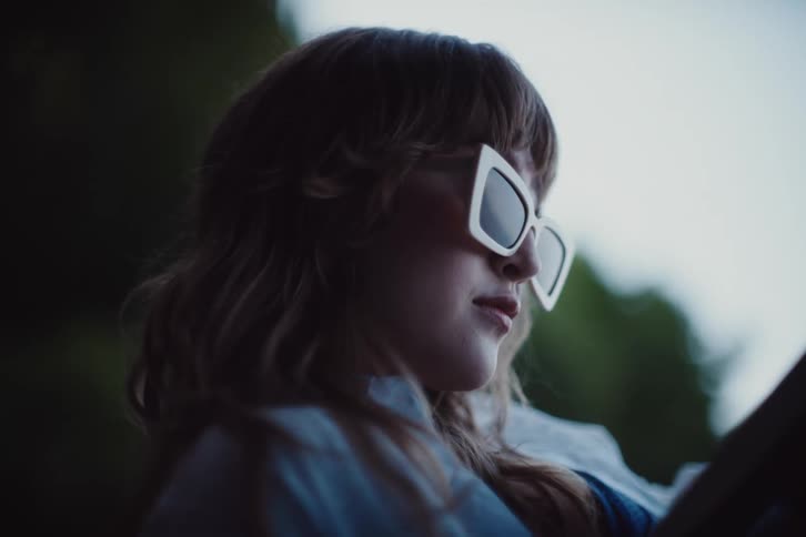 Woman wearing sunglasses sitting in a natural environment