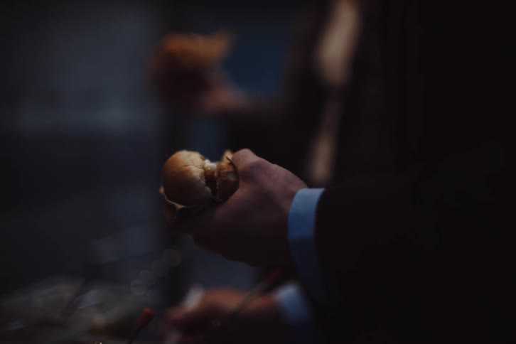 An arm of a person wearing a suit is preparing a hot dog