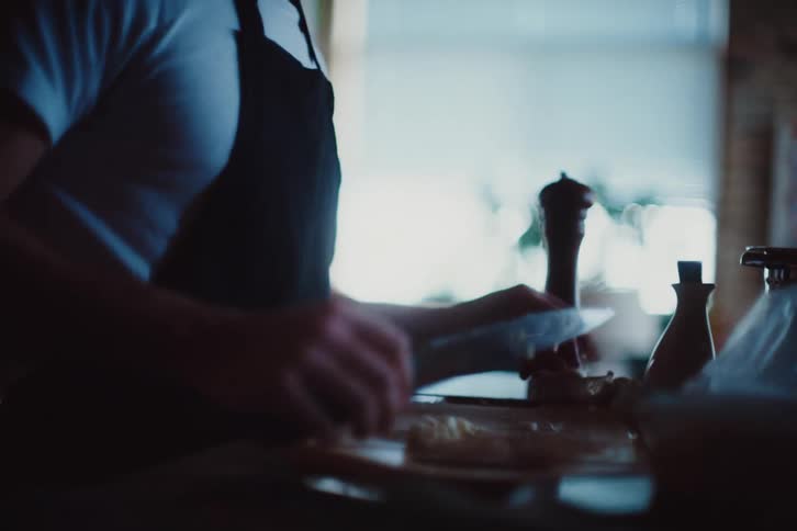 Man in apron holding a knife cooking
