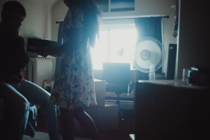 Woman inside a room picking up a box and handing it to a man
