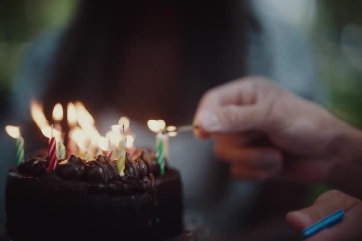 A man lights a colorful candles on a cake and then smiles creating a warm and festive atmosphere