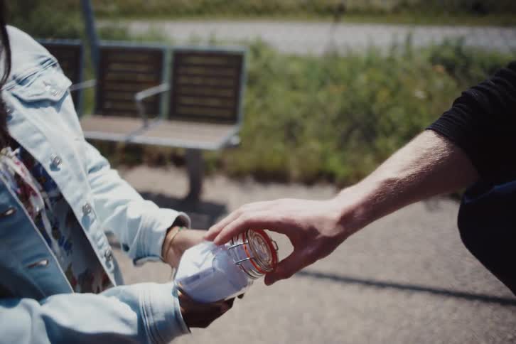 Woman handing a small jar to a man and they both hug