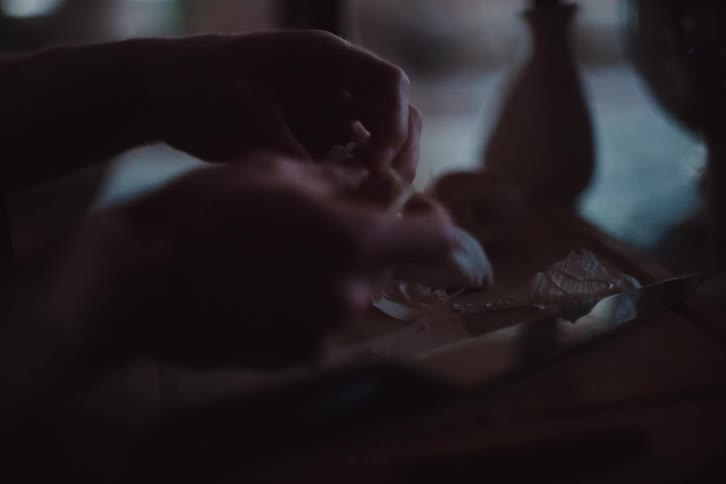 Hands peeling a spice on top of a wooden board