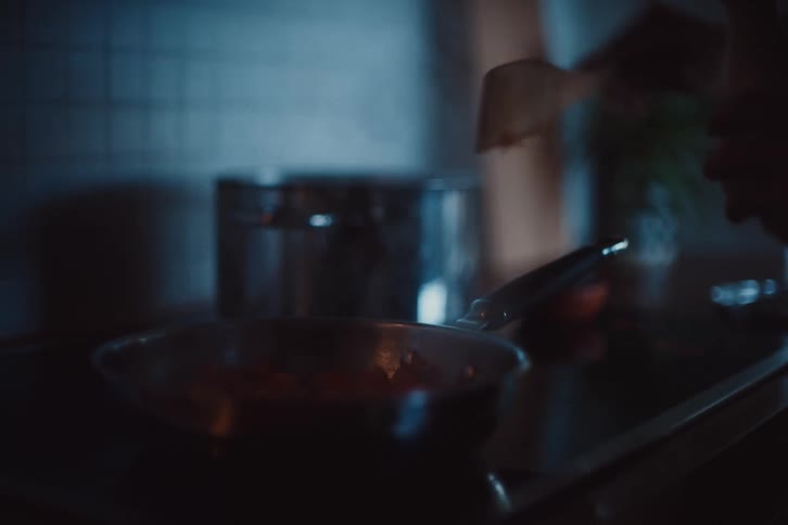 Person with a spatula cooking in a pan and adding seasoning