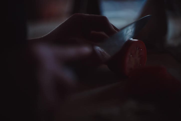 Hand with a knife cutting tomato