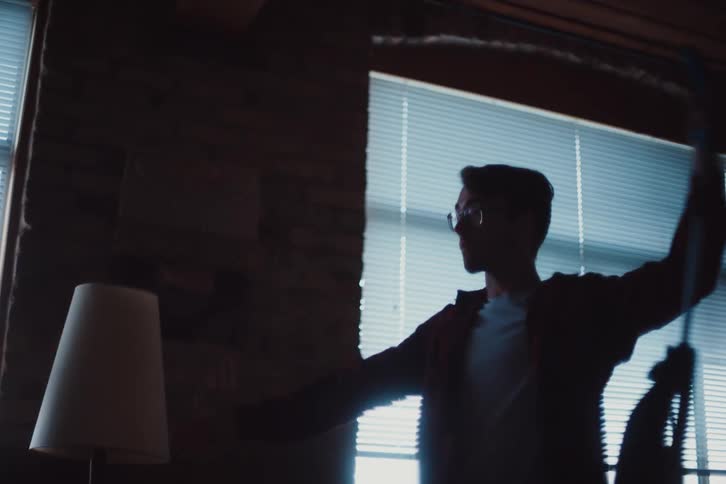 Man in a living room playing with a vacuum cleaner
