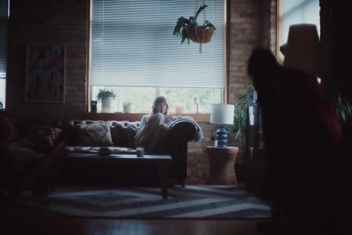 Woman sitting on living room couch and man vacuuming carpet