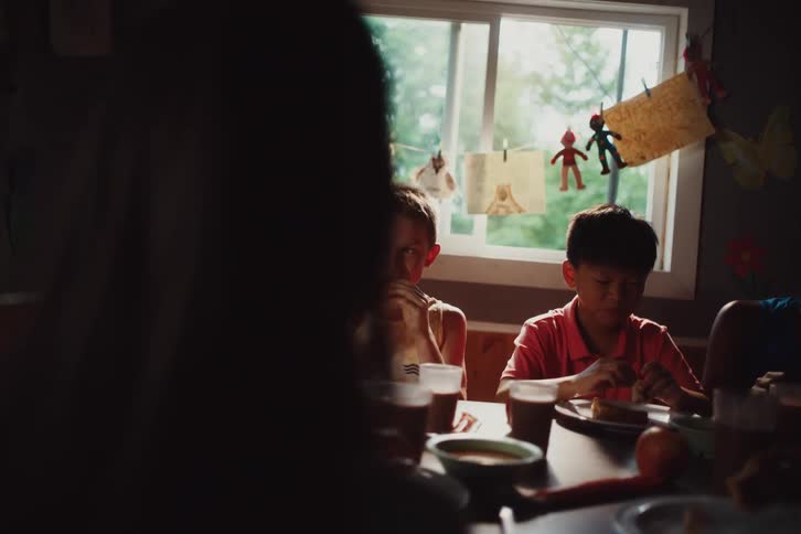 A party with kids both male and female enjoy drinks and a meal at a table