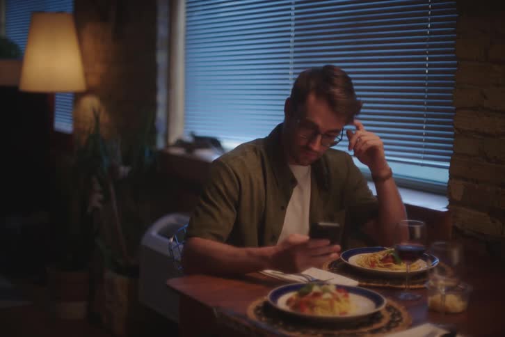 A man uses his phone at the dinner table