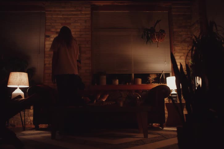 Woman and a man sitting on the couch and while the woman gets up and leaves the room