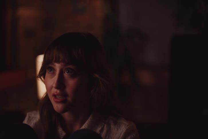 Portrait of a woman sitting and talking in a dimly lit room