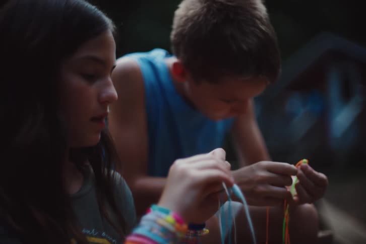 Two children are making jewelry with strings