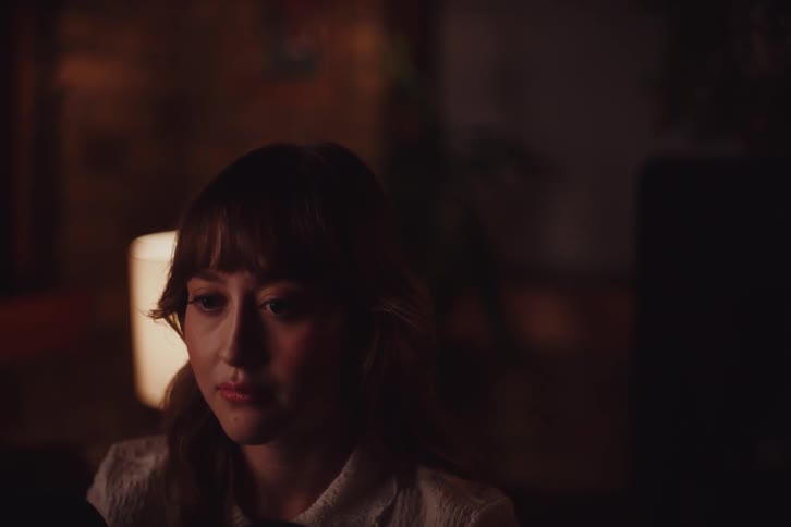 A sad woman sits in a room before getting up and leaving