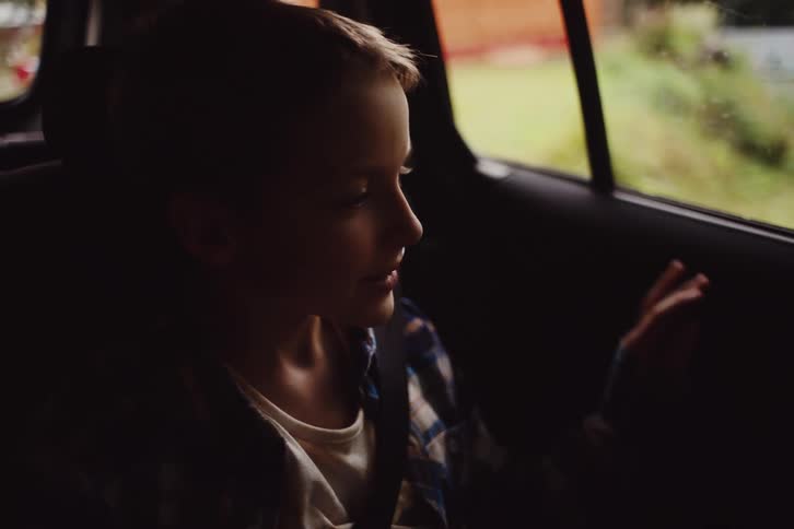 Boy getting into the car and a woman putting on her seatbelt