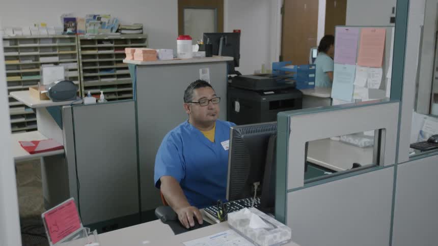 A man in a scrub top works on a computer