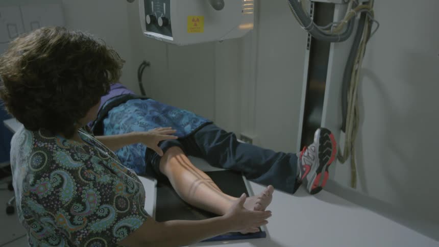 A nurse adjusts a patient's leg position for an x-ray