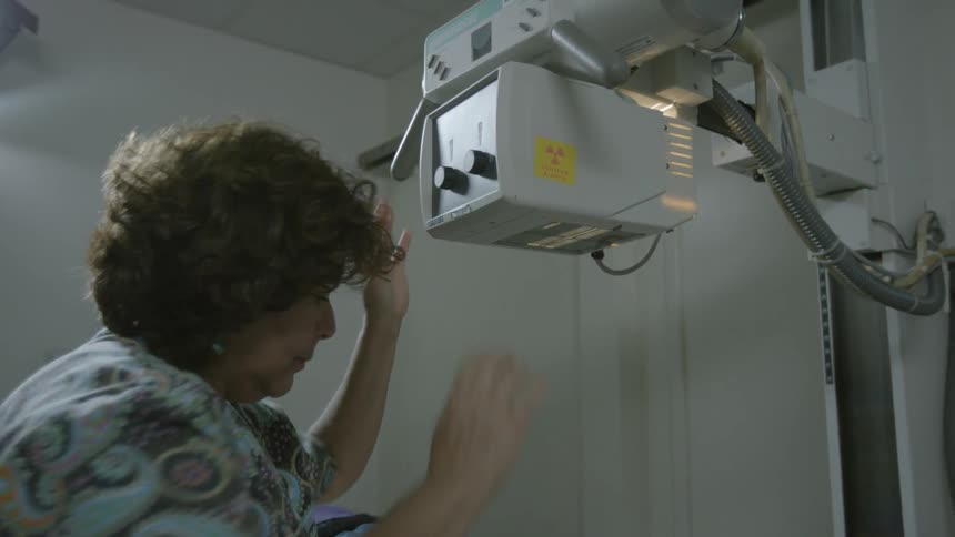 Technician adjusting a piece of equipment preparing to examine a patient's leg