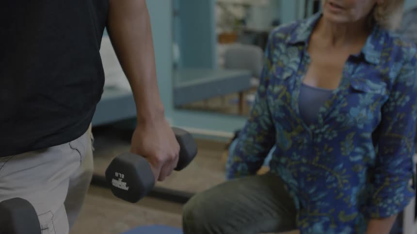 A woman corrects a man's form as he exercises