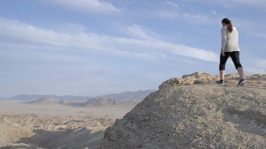 Couple walking towards the edge  of a large rocky area on a partly cloudy day