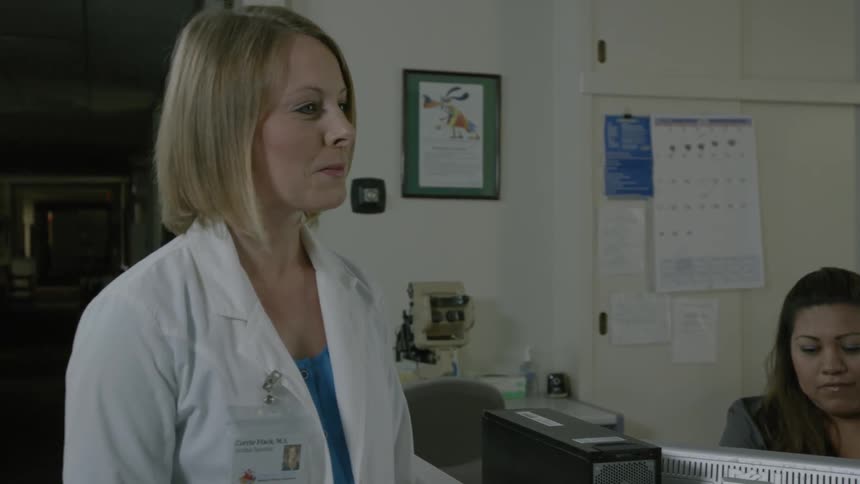 A doctor standing in front of a receptionist in an office is speaking