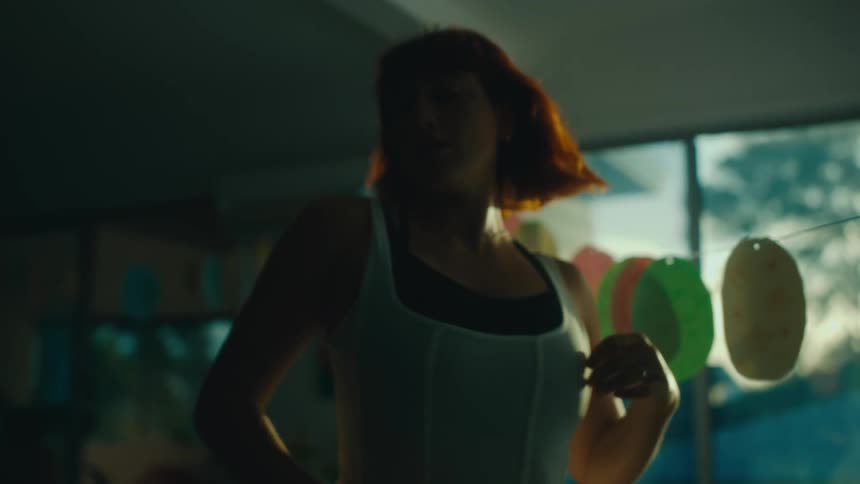 Woman in a white sleeveless blouse dancing indoors