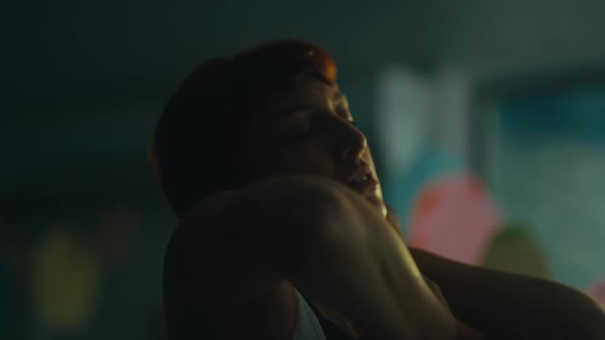 A female dancer dancing gracefully in dim lighting with her eyes closed and arms raised in an expressive pose conveying a serene and introspective mood